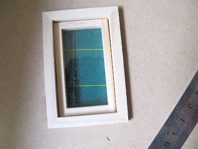 Dolls' house window inserted into a hole cut in a sheet of MDF.
