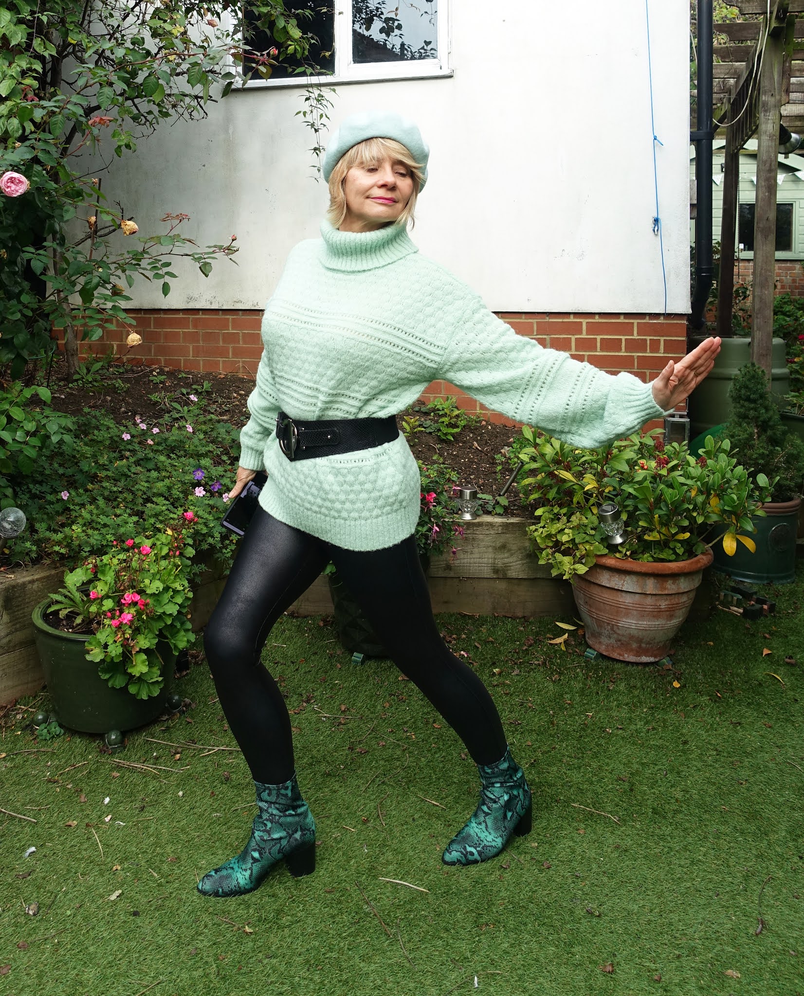 How to style faux leather leggings over 50: Is This Mutton chooses a textured, long mint green jumper, waist cincher belt and mint green beret with snakeskin ankle boots