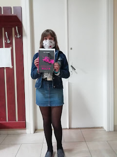 Nastolatka na tle białych podwójnych białych drzwi. Trzyma w rękach książkę.