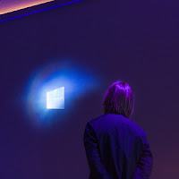 Titelbild: Startet Windows wirklich immer langsamer? Person betrachtet Win-Logo (Quelle: http://news.microsoft.com/de-de/imagegallery)