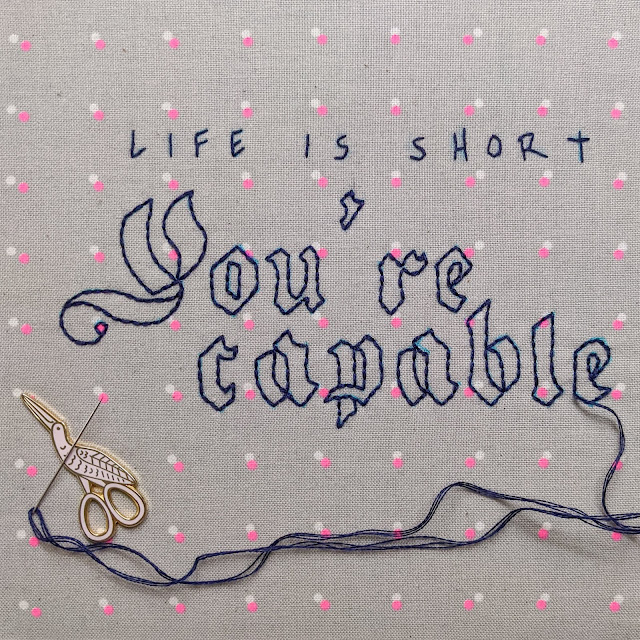 Life is short You're Capable embroidered on dot fabric with needle and thread still there and needle resting on a stork needle minder
