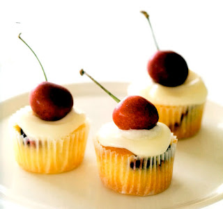 Mini cupcakes with cherries in the batter that are served garnished with a whole cherry.