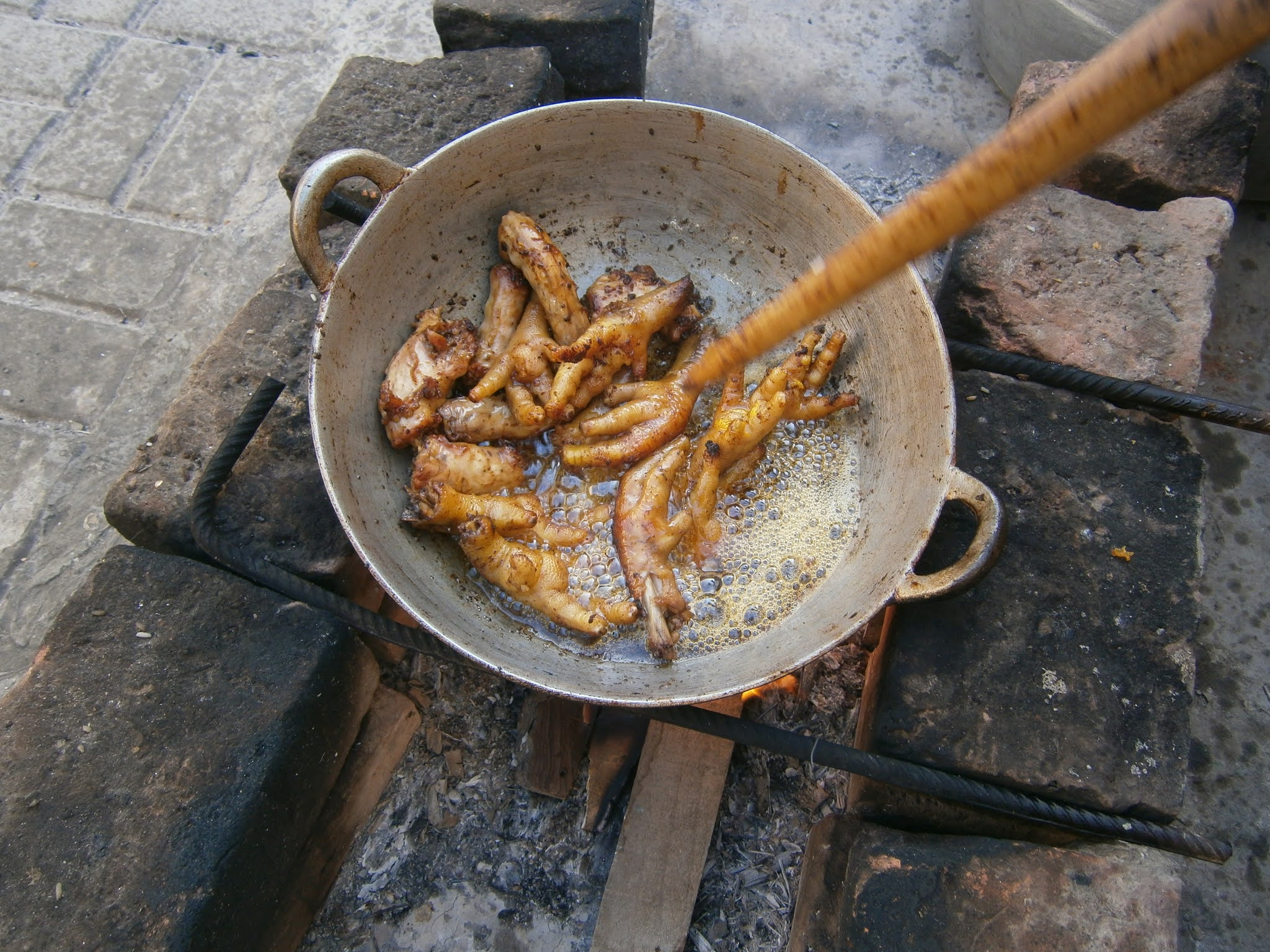 Patas de Pollo frito cocinado en una cocina de leña