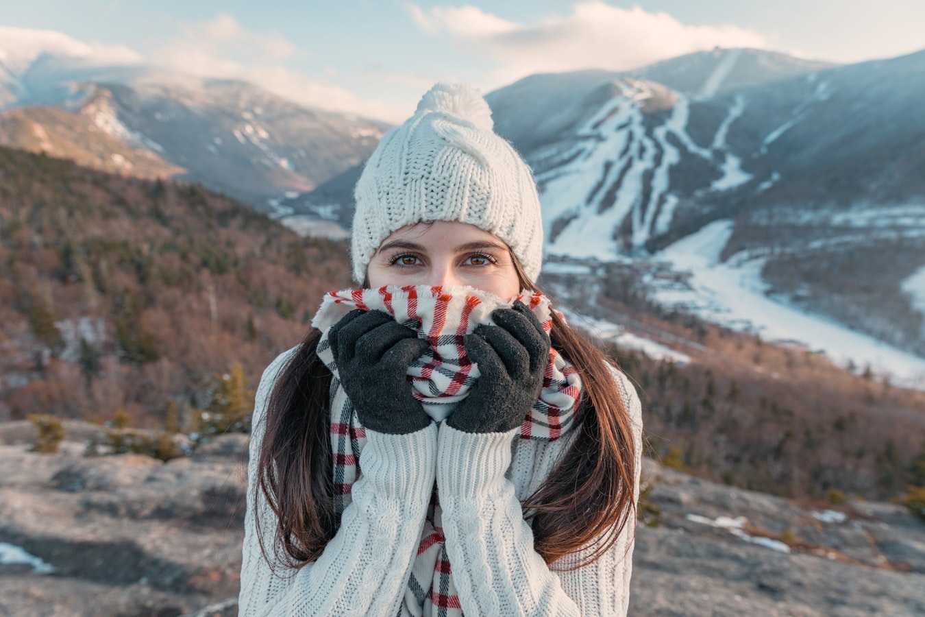 girl wearing sweater, warm hat, scarf and gloves in the mountains