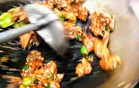 Stir frying chicken manchurian in a wok