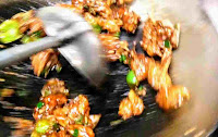 Stir frying chicken manchurian in a wok