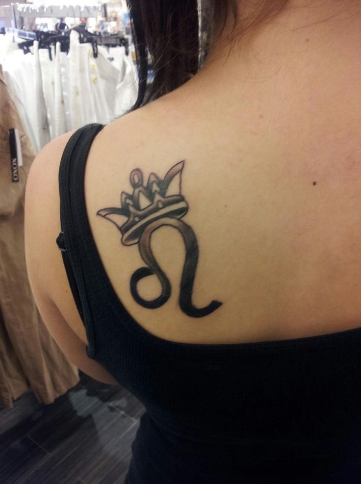 Tatuaje de corona y el simbolo de leo en el omoplato de una chica