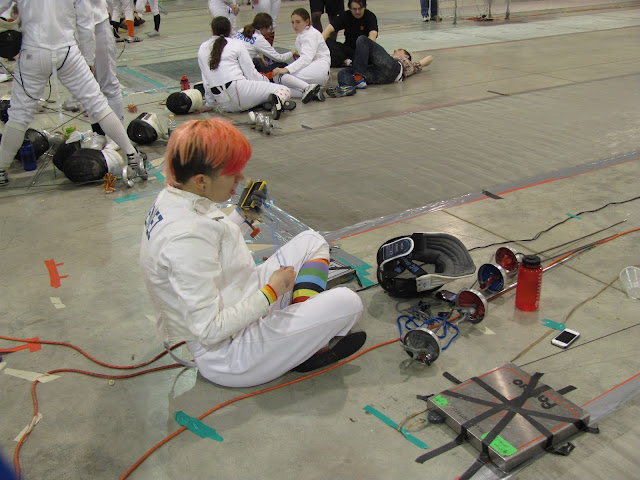 A fencer sits on the floor 