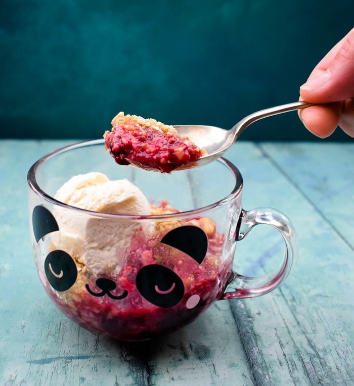 Blackberry vegan hancur Satu sendok remahan blackberry diangkat dari gelas mug