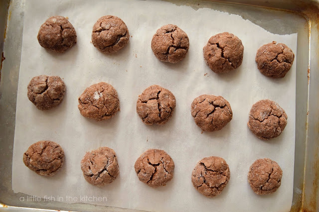 One dozen scrumptious Cappuccino Crinkles are fresh out of the oven and cooling on a rack. The tops of the soft chocolate cookies are perfectly crackled!