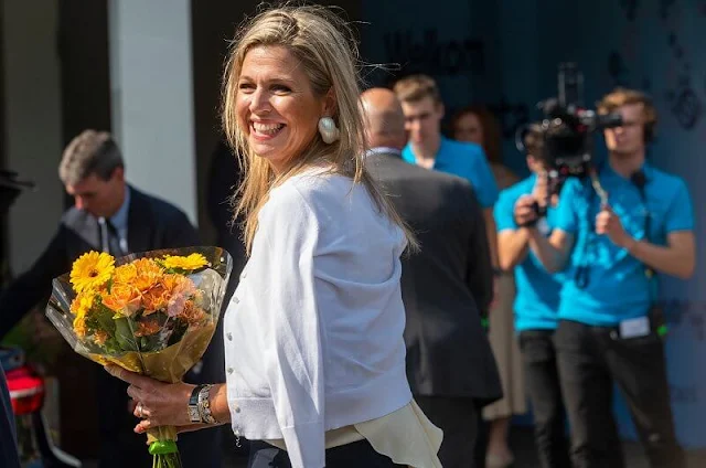 Queen Maxima wore gold tone and shell clip earrings by Prada. Queen Maxima wore a sleeveless high neck silk shirt by Zara, Natan