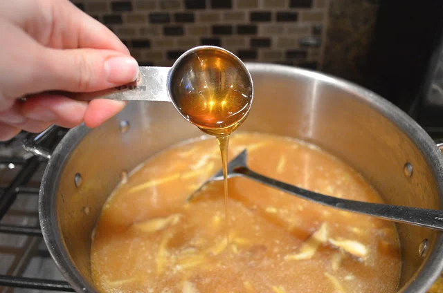 A tablespoon of Honey being added to the pot of Hot and Sour Chicken Soup.