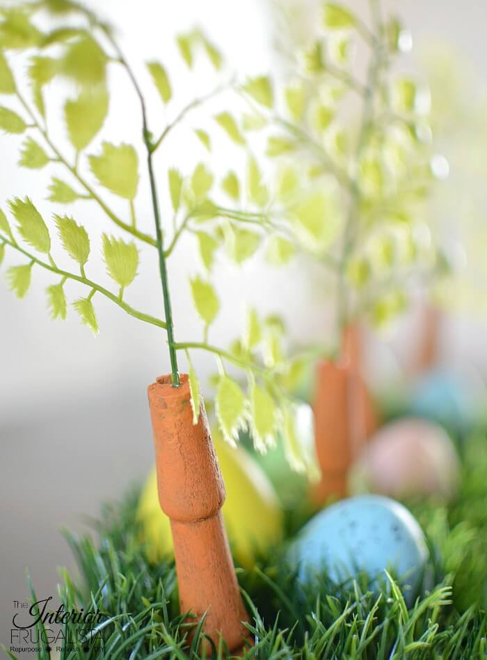 An upcycled Easter centerpiece box with faux wheatgrass, chair spindle carrots, and DIY speckled eggs for a fun budget Easter table decoration idea.