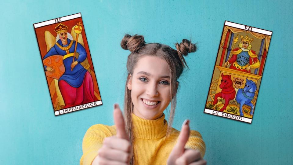 une femme souriante les pouces relevés entourée de cartes de tarot