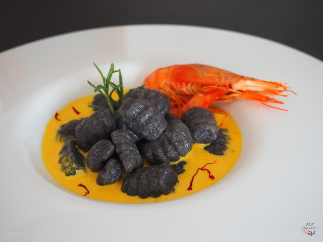 Gnocchi al nero di sepia y aroma marinero, con salsa de gambas y azafrán