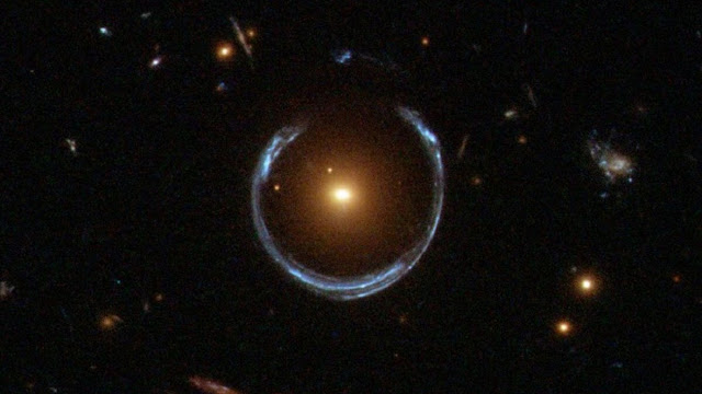Это почти замкнутое в кольцо изображение галактики — результат прохождения света через гравитационную линзу LRG 3-757.  Фото: ESA/Hubble & NASA