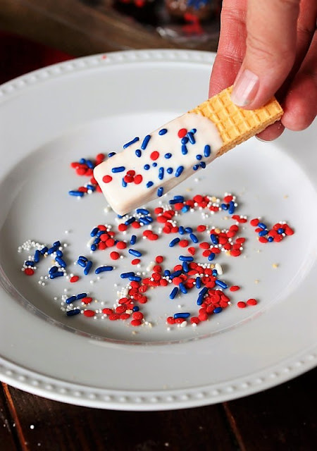 Sprinkling a Sugar Wafer with Red White & Blue Sprinkles Image