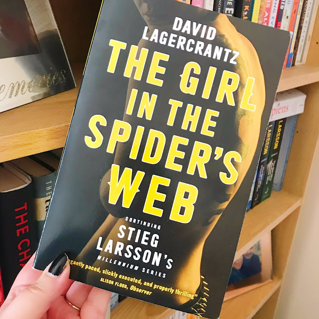 The girl in the spider's web by david lagercrantz held up in front of bookshelf
