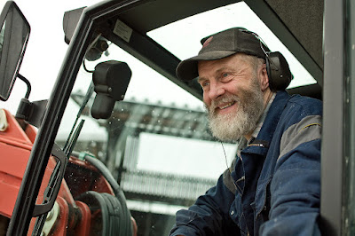 En leende Jan Karlsson i traktor med dörren öppen