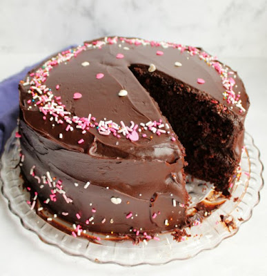 Chocolate cake that is devilishly good. This cake is rich, moist, delicious and super simple to put together. All you need is a bowl, a whisk and a little bit of time. layered chocolate cake with shiny chocolate frosting and sprinkles