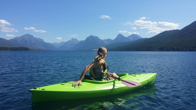 Girl looking at the mountains in her green kayak
