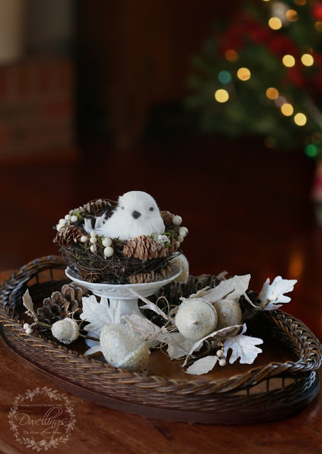Snow bird in a nest with glittery pine cones and acorns.