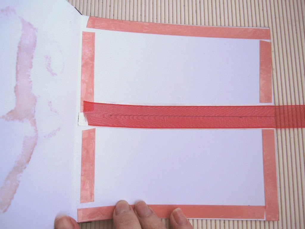 paso 6a tutorial mini-álbum scrapbook, interior de la tarjeta con cinta adhesiva de doble cara pegada en los bordes y en el centro cinta de gasa roja para uno de los cierres