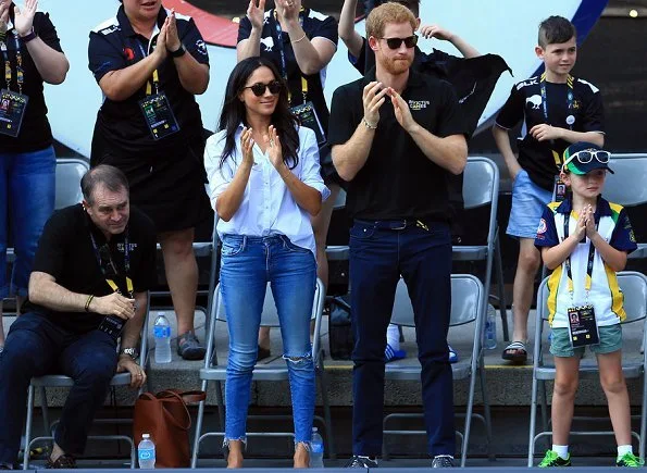 Prince Harry and Meghan Markle watched Wheelchair Tennis match. Style of Meghan Markle. wore a ice blue blouse and jeans