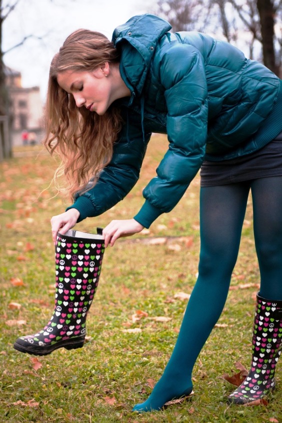 Woman wearing black mini skirt, blue tights and emoji print rain boots