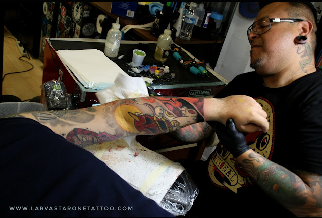 Horipeppe mukade of zero one ink holding an irezumi style tattooed arm at his tattoo station