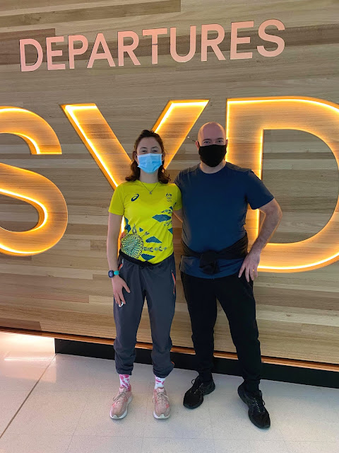 Such an important pic this one. After a long road to the Olympics here there are – Marina and Joe at Sydney International Airport Departures. The stand in front of the wooden wall with ‘departures SYD’ in lit letters. Marina on the left in her Olympic teamwear, Joe on the right understated in black and dark blue. Poised, strong and ready. Forza!