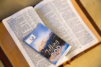 Bíblia aberta com folheto em cima escrito Fale com Deus