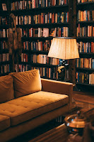 Imagen de una lámpara de pie junto a un sofá delante de una estantería repleta de libros