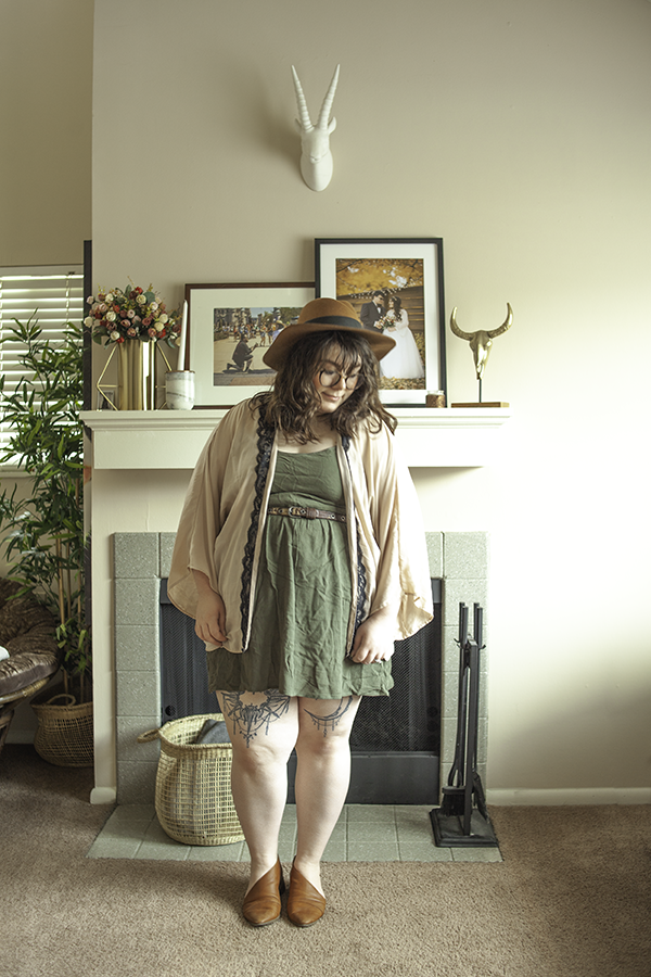An outfit consisting of a brown panama hat, dusty pink "kimono" with black lace trim, olive green mini dress, and brown d'orsay flats. 