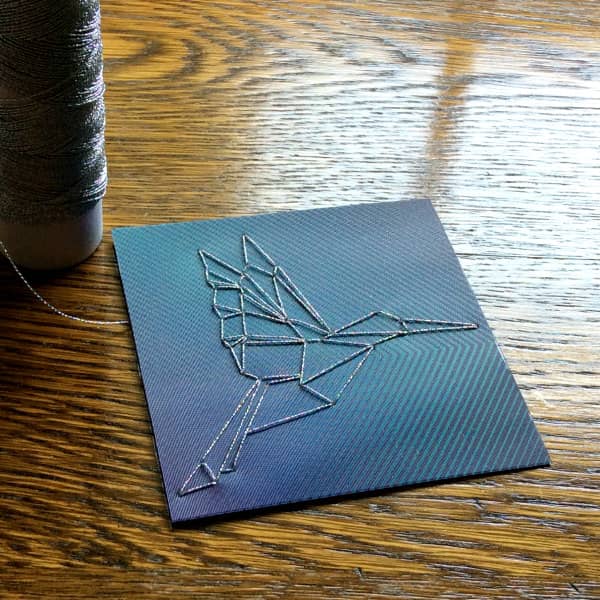 stitched hummingbird paper craft project with spool of metallic thread