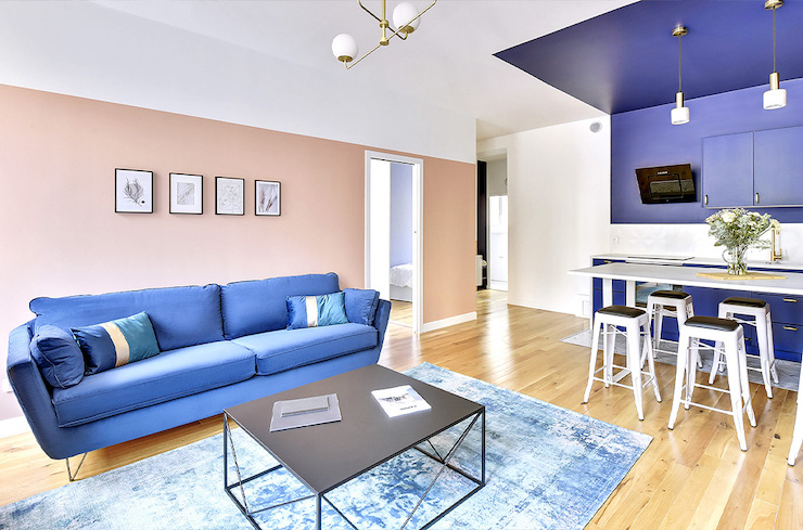 Salón clásico moderno con sofá azul y pared salmón.