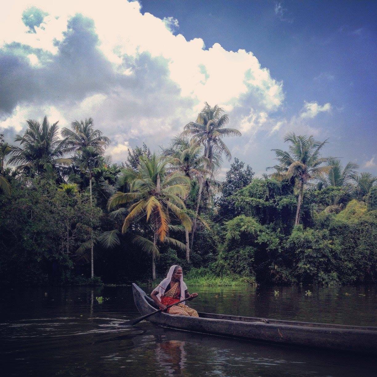 lady in sari rowing wooden boat on river kerala india