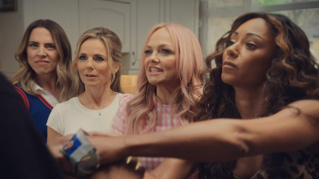 Spice Girls looking unhappy as they try to get crisps off the man