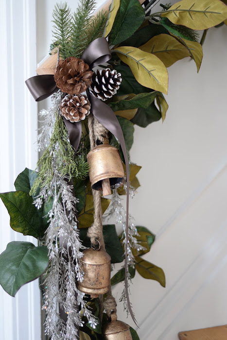 magnolia garland on stair handrail, brass bells, brown satin ribbon