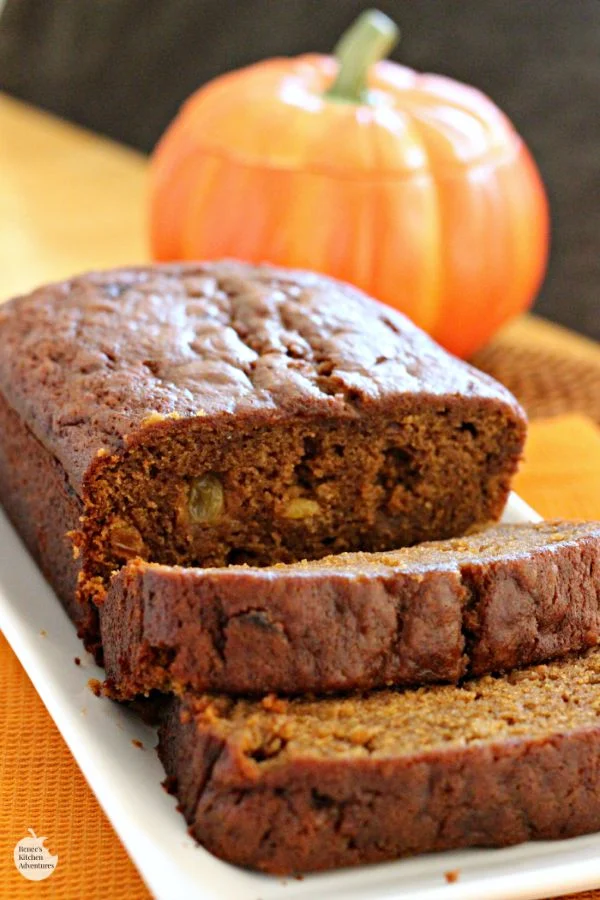 Spiced Pumpkin Bread by Renee's Kitchen Adventures on a white tray sliced with a pumpkin in the background