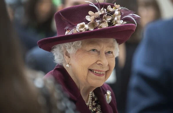 Queen Elizabeth II visited the headquarters of MI5 at Thames House in London. burgundy coat, gold brooch, floral dress