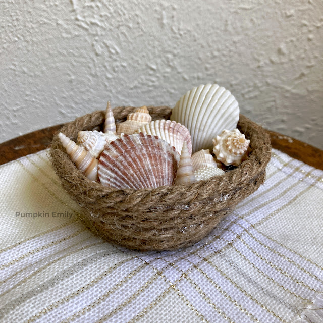 A rope bowl filled with seashells.