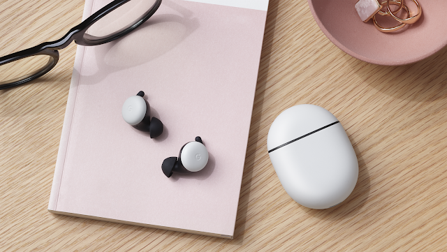 Pixel Buds e custodia su un tavolo di legno con quaderno rosa e occhiali.