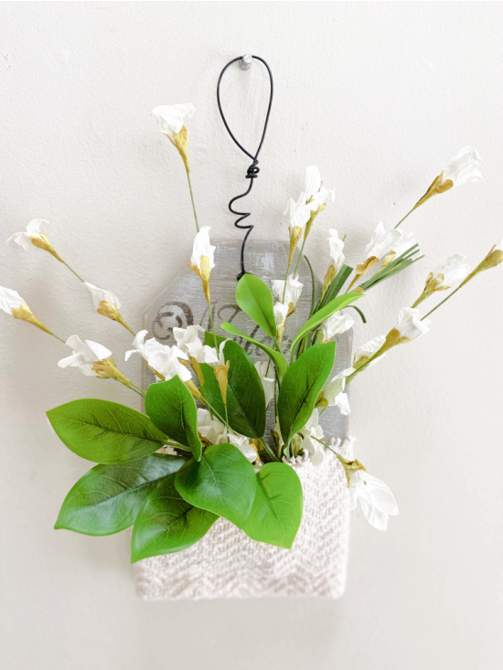hanging wall pocket filled with white flowers and greens