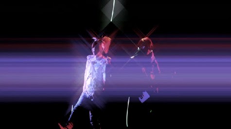 Maya and Aiji perform with starburst lighting effects.