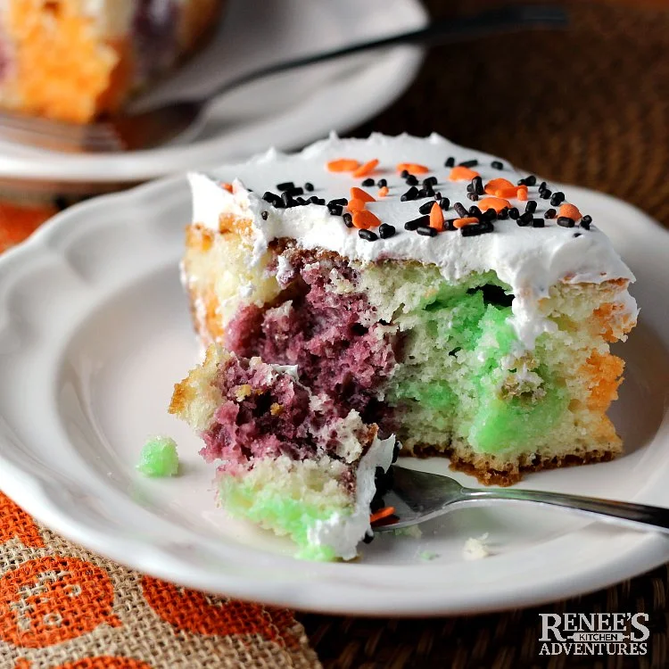 Piece of Halloween Jello Poke Cake by Renee's Kitchen Adventures on a white plate with a bite on the fork ready to eat