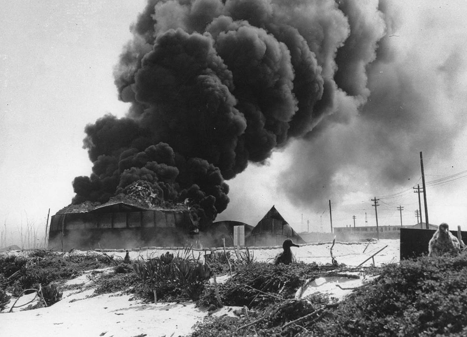 Black smoke rises from a burning U.S. oil tank, set afire during a Japanese air raid on Naval Air Station Midway on Midway Atoll, on June 4, 1942. American forces maintained an airstrip with dozens of aircraft stationed on the tiny island. The attack inflicted heavy damage, but the airstrip was still usable.