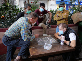 Men playing and watching xiangqi while wearing surgical masks
