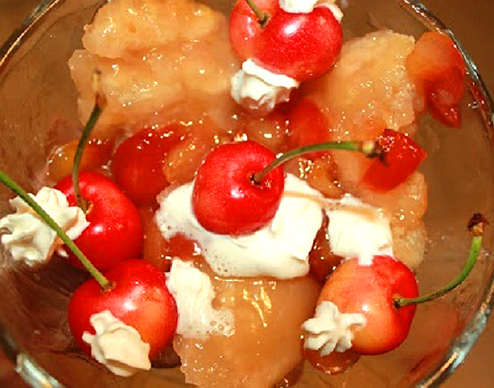 Rainier Cherry Muffins or Rainier Cherry Cobbler Recipe this is a bowl of cobbler using rainier cherries for the recipe in a glass bowl with whipped cream