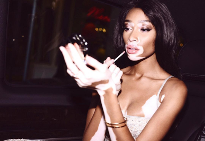 Image of hollywood model winnie harlow applying lipstick at the back of a car